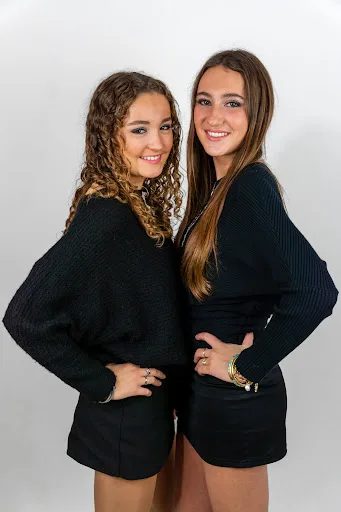 Portrait studio de deux jeunes femmes en pull noir, fond blanc