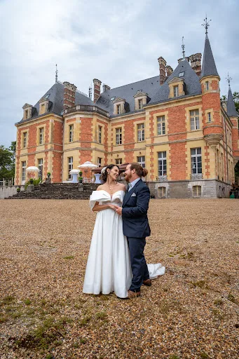 Les mariés se faisant face devant un château, allée gravillonnée